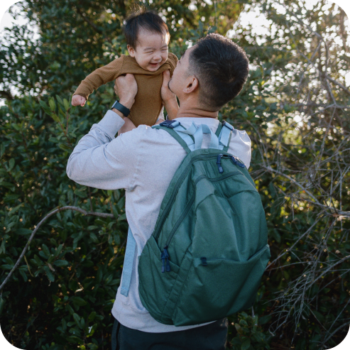 dad holding baby up while wearing state diaper backpack