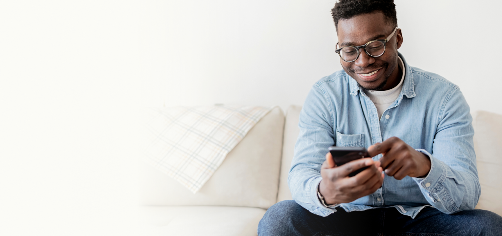 man looking at phone while sitting on couch